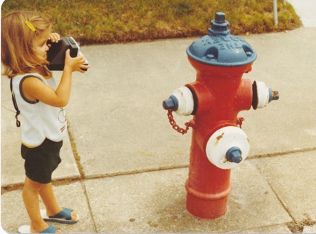 picture of a little girl with a polaroid camera and a fire hydrant practicing photography