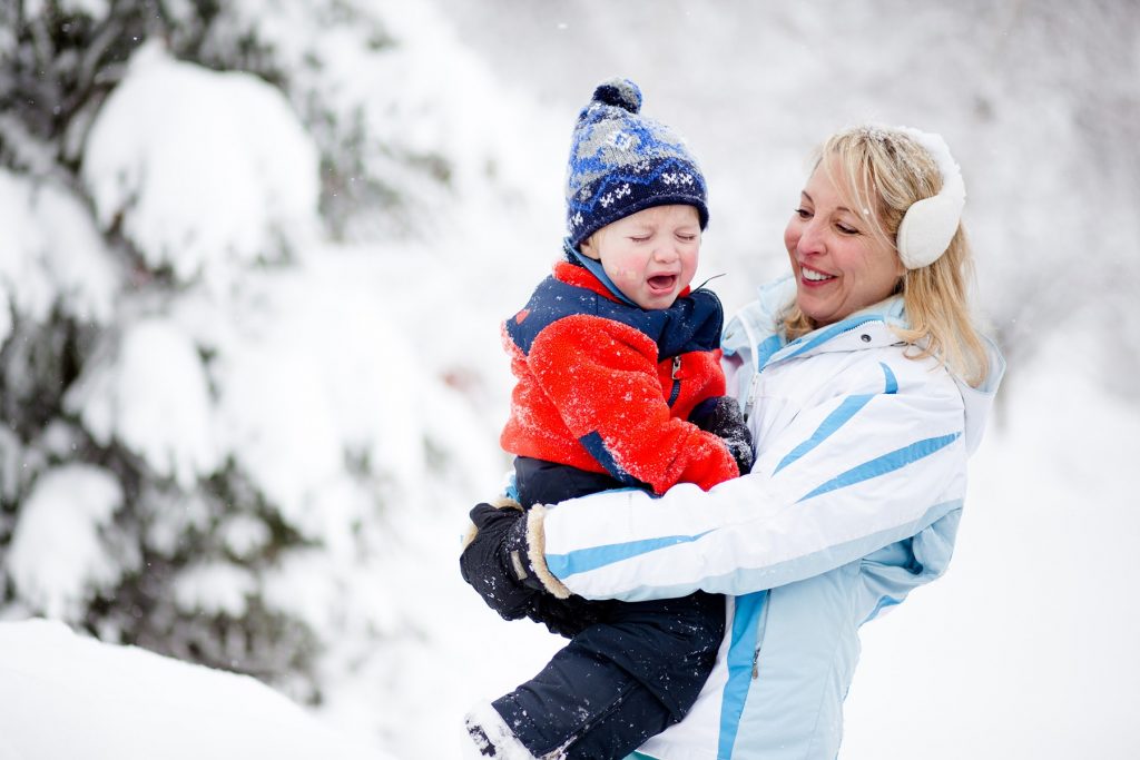 mama holds her son in the snow and he is crying