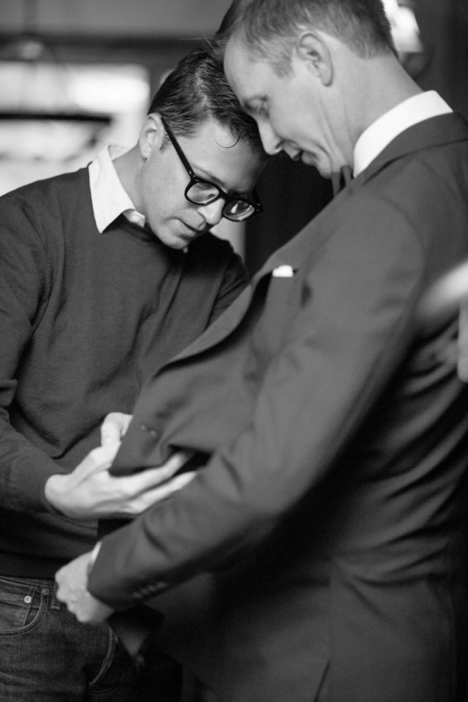 friend helps groom with his suit