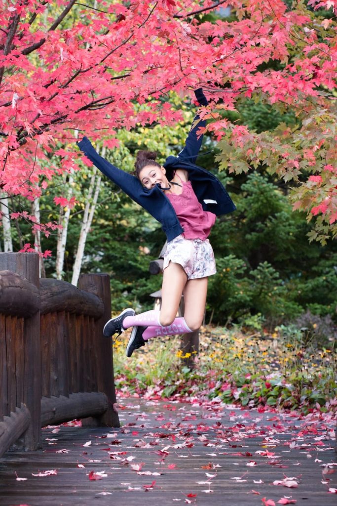 little girl jumps in the colored trees