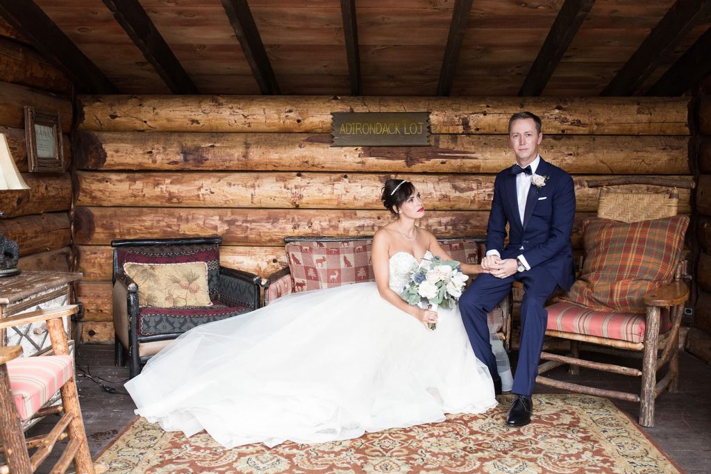 groom and bride sit in a log cabin