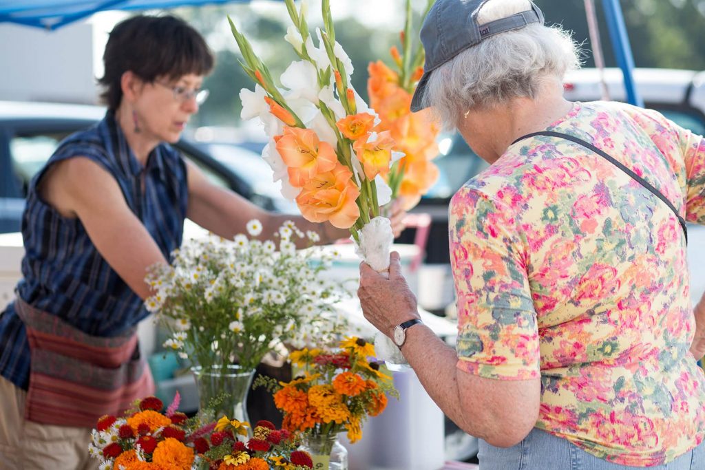 a woman purchases a bouquet of orange flowers