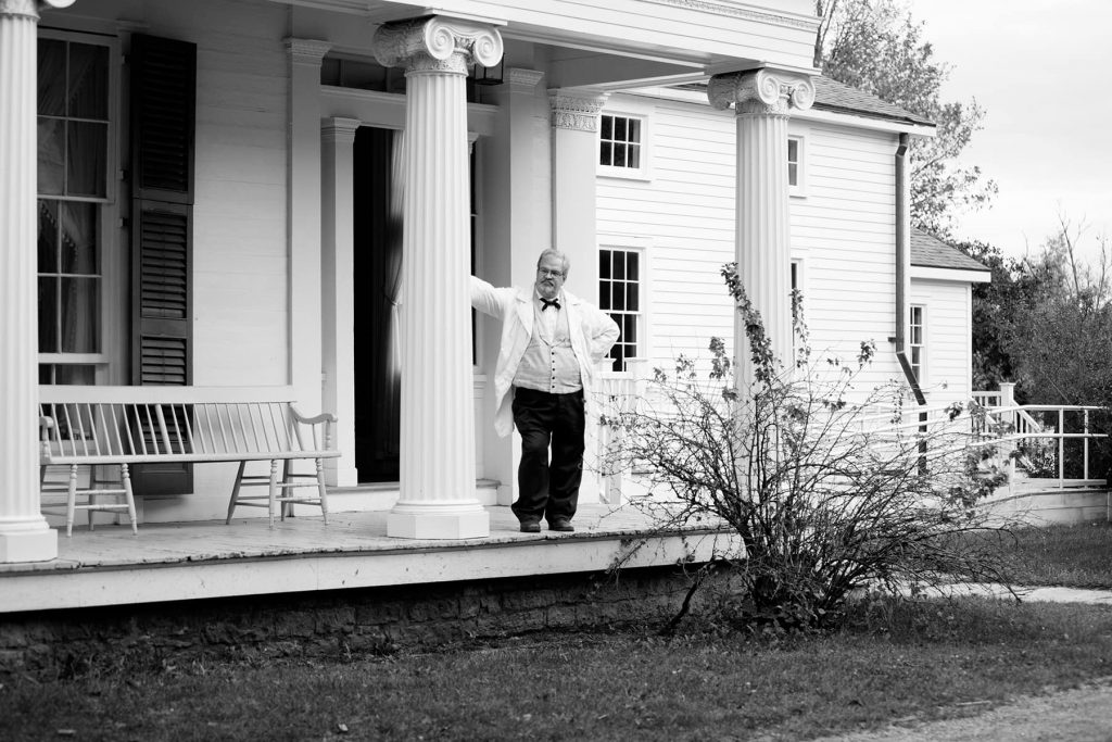 a man waits on the porch entrance of a home in the village
