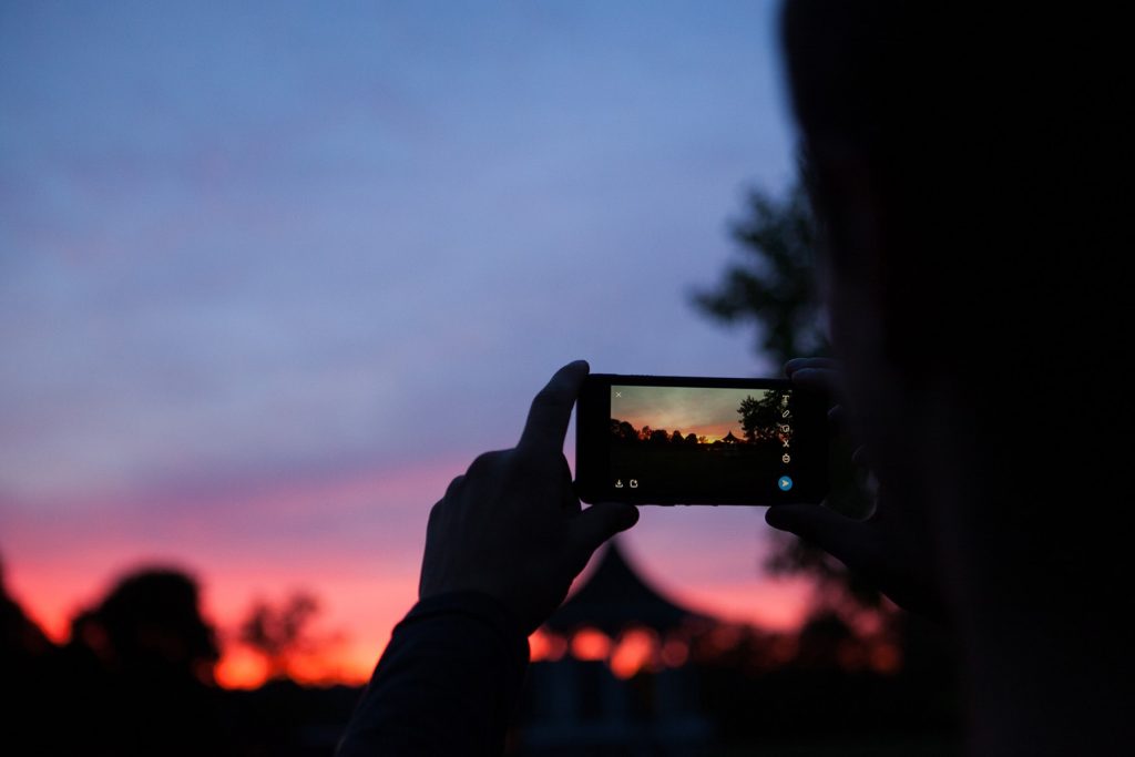 person takes a sunset picture through camera