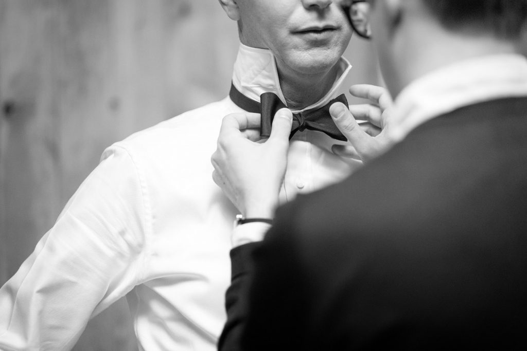 groom has his tie straightened by his best man before marrying his wife