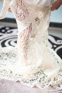 bride putting on her lace wedding gown