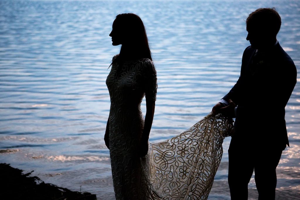 silhouette of bride and groom against the water of irondequoit bay at the end of a two-day wedding