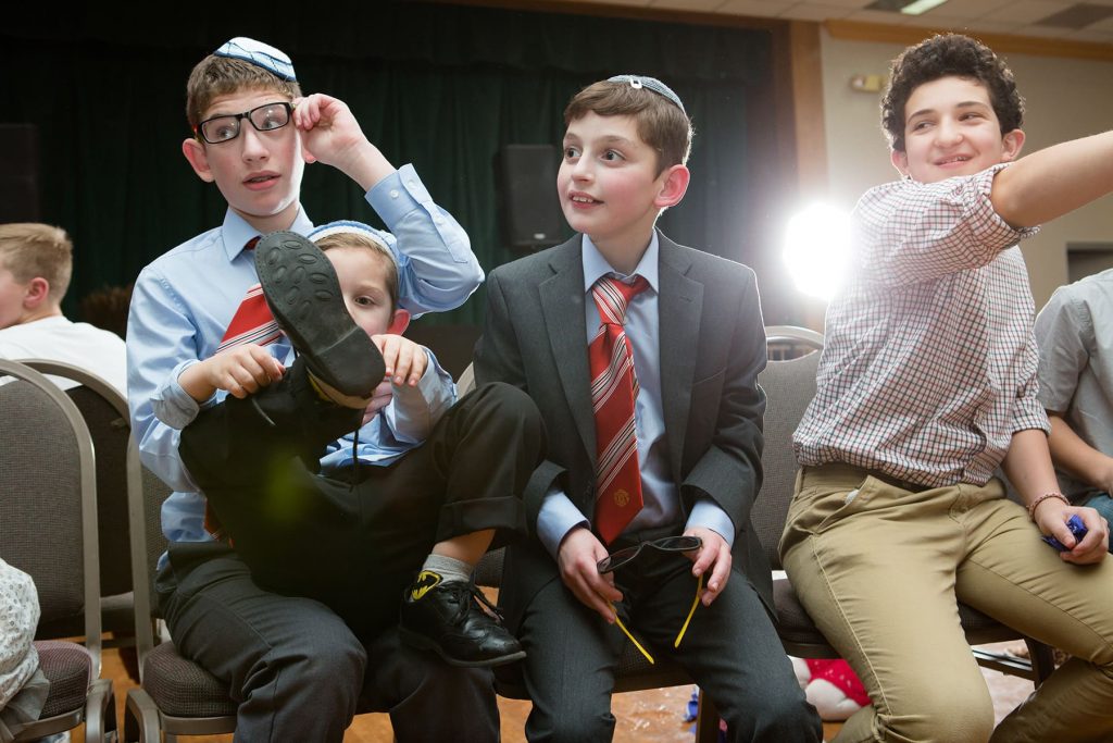 4 children sit in chairs while playing fun games at a mitzvah celebration