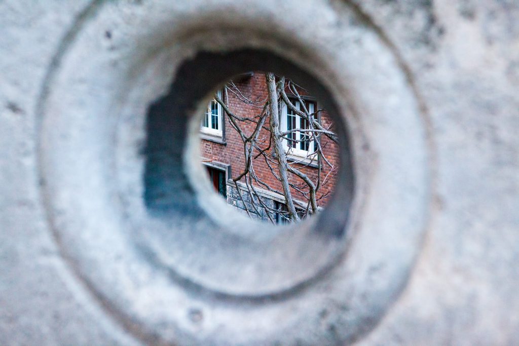 the view of a brick building through a hold in a wall
