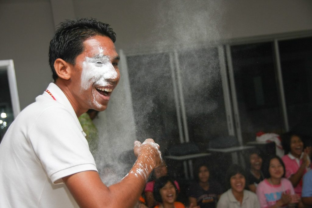 a teacher is splashed with baby powder as part of tradition from his students on a retreat