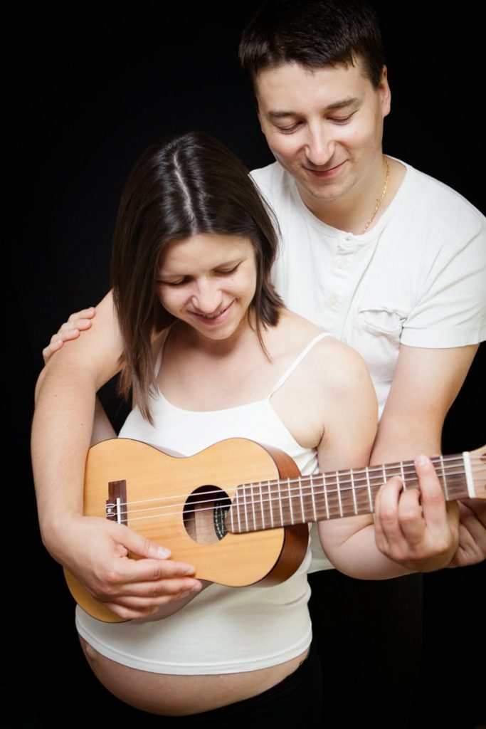 man playing guitar for his unborn son inside his wife's belly